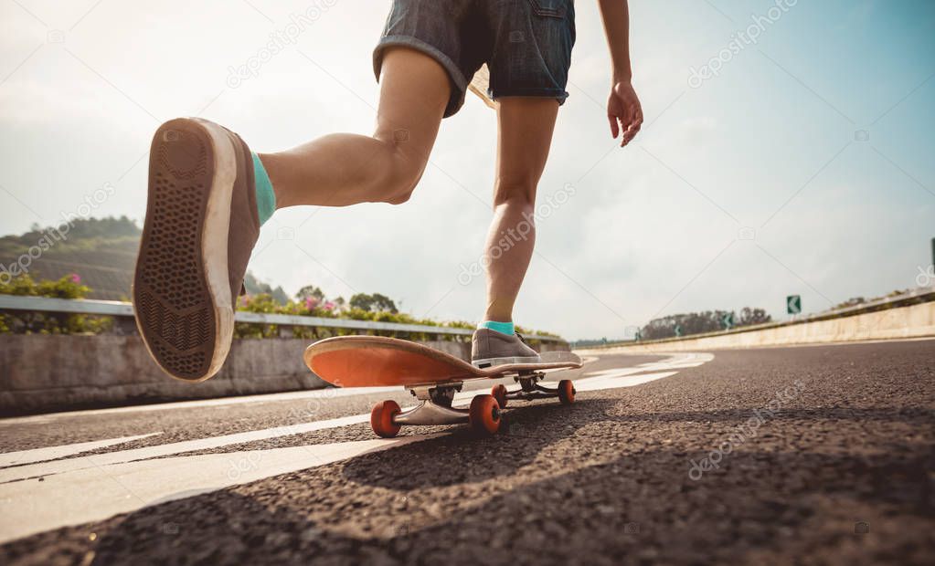 Female skateboarder skateboarding on empty urban city highway 