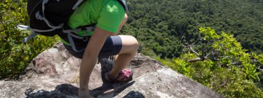 Başarılı kadın yürüyüşçü dağın zirvesine tırmanıyor.