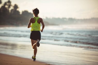 Gün doğumu plajda çalışan fitness kadın 