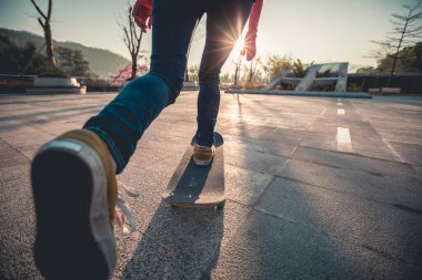 Gün doğumunda kaykay yapan kadın kaykaycının alt kısmı.