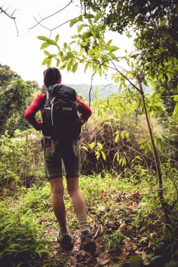 Genç bayan yürüyüşçü bahar dağlarında yolda yürüyor.