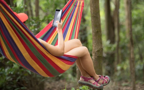 在热带雨林用智能手机在吊床上放松女人 — 图库照片