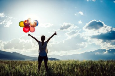 Renkli balonlarla otlakta duran genç bayana tezahürat yapıyor.