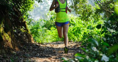 Gündoğumunda tropikal ormanda koşan genç bir kadın 