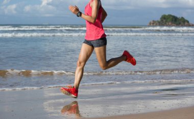 Sahilde koşan genç fitness kadını.