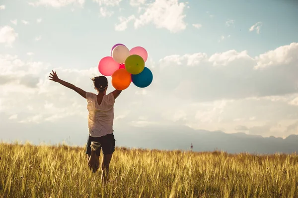 Torcendo Jovem Correndo Pastagens Com Balões Coloridos Braços Levantados — Fotografia de Stock