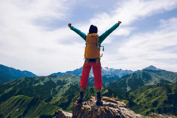 山の上の崖の端に立って腕を伸ばしている強力な女性ハイカー — ストック写真