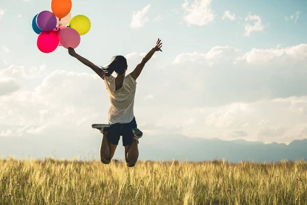 Torcendo Jovem Saltando Pastagens Com Balões Coloridos Braços Levantados — Fotografia de Stock