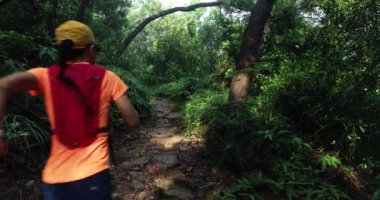 Genç bayan gezgin tropikal ormanda koşuyor. 