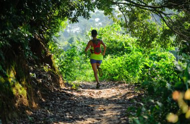 Gündoğumunda tropikal ormanda koşan genç bir kadın 