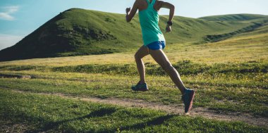 Genç fitness kadın patika koşucusu çayırlarda koşuyor