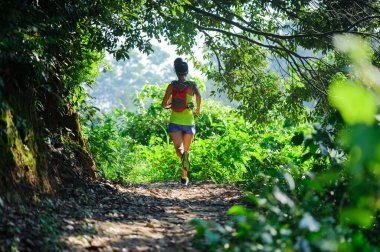 Gündoğumunda tropikal ormanda koşan genç bir kadın 