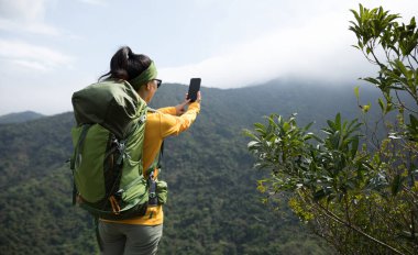 Dağın tepesinde akıllı telefon kullanan başarılı bir yürüyüşçü 