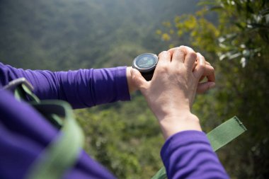 Başarılı yürüyüşçünün elleri dağın tepesinde yüksekliği kontrol ediyor