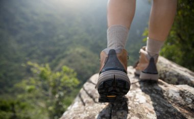 Başarılı yürüyüşçülerin bacakları dağın tepesinde manzaranın tadını çıkarıyor.