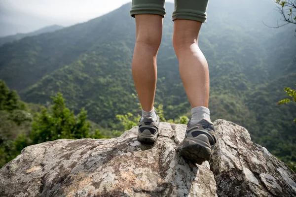 成功的徒步旅行者在山顶悬崖边欣赏风景的腿 — 图库照片