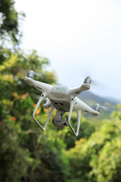 White drone with camera flying in tropical forest