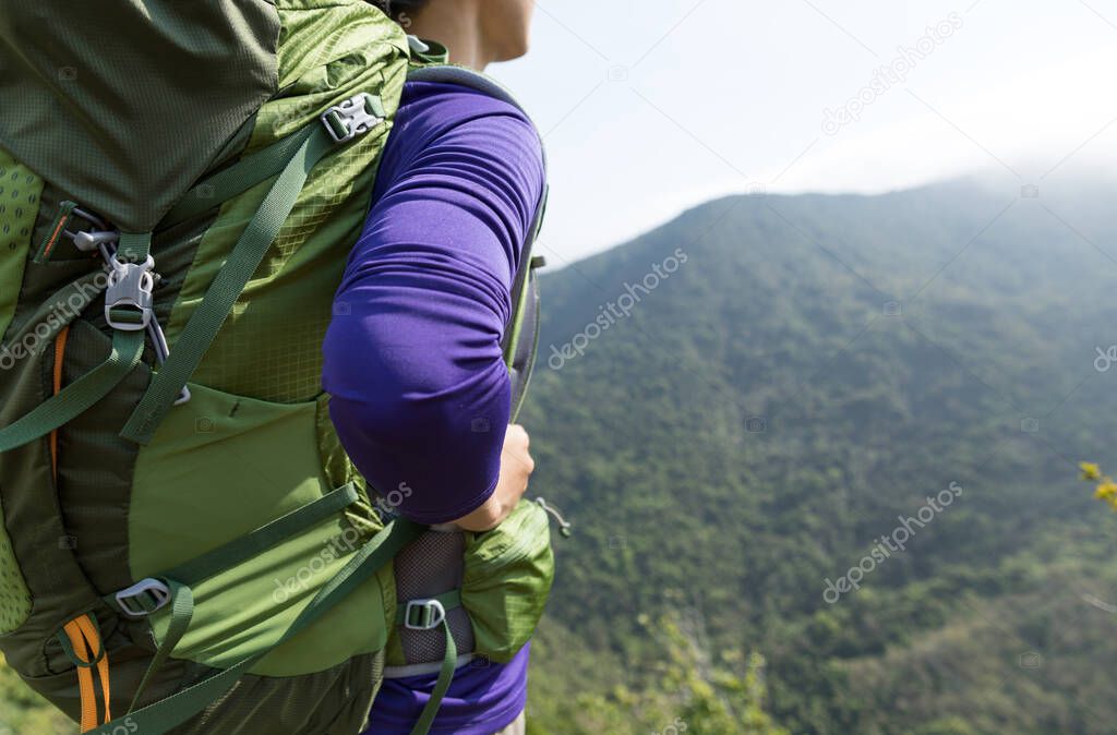 Female successful hiker enjoying view on cliff edge of mountain top
