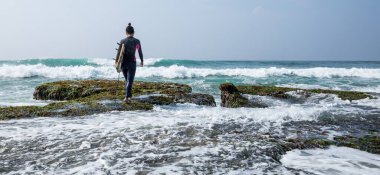 Sörf tahtası olan dişi sörfçü.