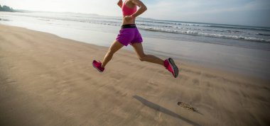 Güneş doğarken sahilde koşan sağlıklı bir kadın. 