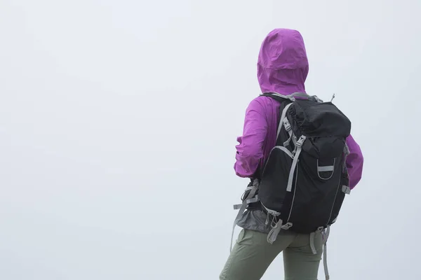 Woman hiking on trail at foggy mountain top