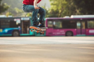 Kaykaycı dışarıda kaykayla numaralar yapıyor.