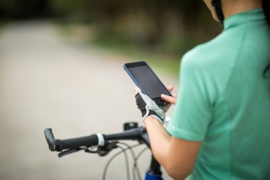 Bisikletçi orman yolunda dağ bisikleti sürerken navigasyon için akıllı telefon kullanır