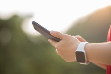 Açık havada akıllı telefon kullanan eller.