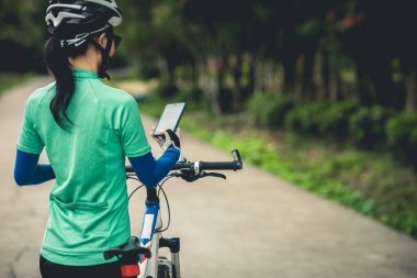 Bisikletçi orman yolunda dağ bisikleti sürerken navigasyon için akıllı telefon kullanır