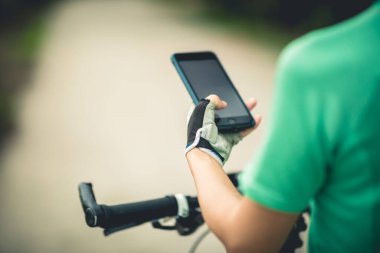 Bisikletçi orman yolunda dağ bisikleti sürerken navigasyon için akıllı telefon kullanır