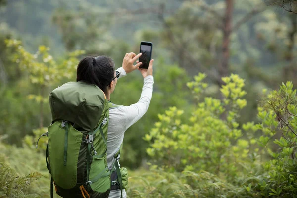在春山用智能手机拍照的女徒步旅行者 — 图库照片
