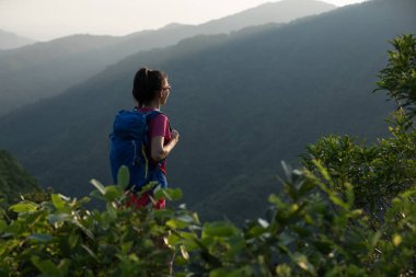 Başarılı bir yürüyüşçü yaz gündoğumu dağının zirvesinde yürüyüş yapıyor.