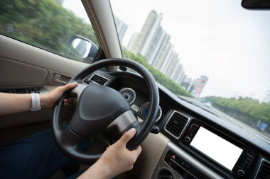 İnsanlar şehir yolunda araba sürerken direksiyon başında el ele tutuşuyorlar.