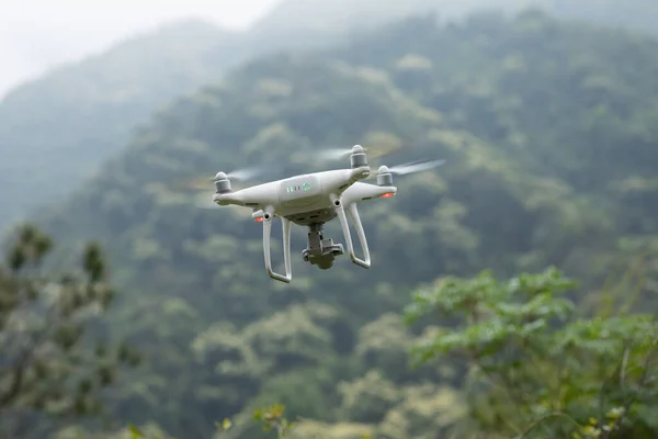 White drone with camera flying in spring mountains