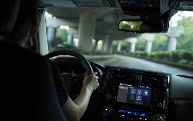 İnsanlar şehir yolunda araba sürerken direksiyon başında el ele tutuşuyorlar.