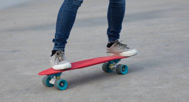 Kaykaycı bacakları açık havada kaykay yaparken görülüyor.