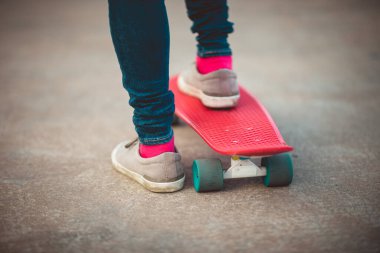 Kaykaycı bacakları açık havada kaykay yaparken görülüyor.