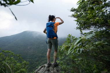 Başarılı bir yürüyüşçü, dağların tepesindeki gündoğumu manzarasına bakıyor.