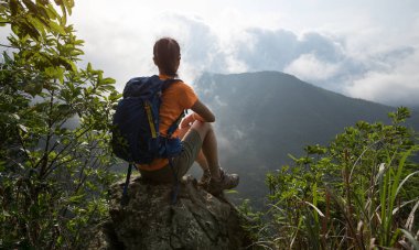 Başarılı bir yürüyüşçü, dağların tepesindeki gündoğumu manzarasına bakıyor.