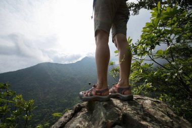 Başarılı yürüyüşçü, dağın tepesindeki güneşin manzarasının tadını çıkar.