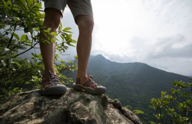 Başarılı yürüyüşçü, dağın tepesindeki güneşin manzarasının tadını çıkar.