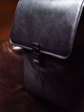 Siyah deri bir iş çantası deri bir sandalyede oturuyor.