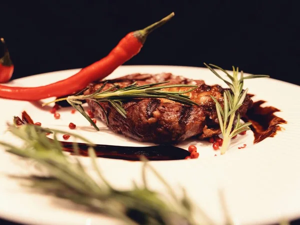 Toasted meat steak on a black background with red chili sauce — 스톡 사진