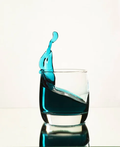 Un chorrito de alcohol azul en un vaso de whisky —  Fotos de Stock