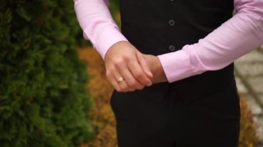 Bir adam pembe gömleğini ilikliyor.