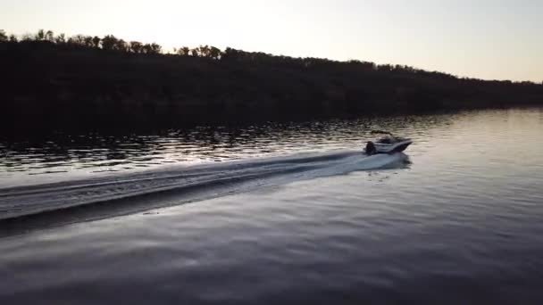 Barco a motor flotando en el río al atardecer — Vídeo de stock