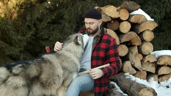 Brutaler Holzfäller spielt mit Hund im Hintergrund des Waldes — Stockfoto