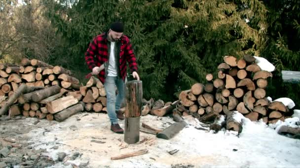 Brute houthakker hakken hout in het winterbos — Stockvideo