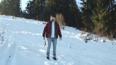  Zalim oduncu elinde baltayla karlı bir yamaçtan geçiyor.