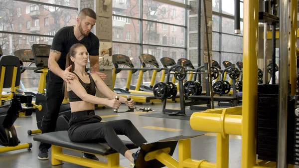 Spor salonunda kürek çekerek antrenman yapan genç bir kadın.